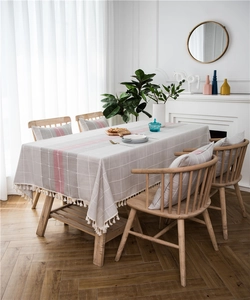 Detail of grey plaid table runner with pink stripes and white cotton fringe tassels