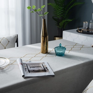 Detailed view of grey embroidered rectangular tablecloth with gold geometric lattice