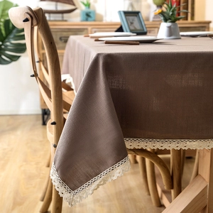 Close-up of dark brown linen tablecloth with elegant beige crochet lace fringe detail