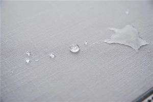 Macro shot of light gray faux linen table runner fabric with waterproof water beads