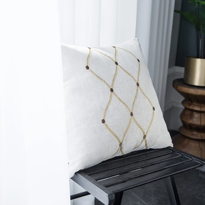 Close-up of geometric diamond embroidery on a cream linen pillowcase for home decor