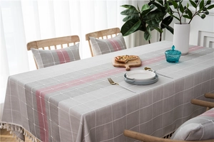 Detail view of grey plaid table runner with red stripes and elegant white tassels