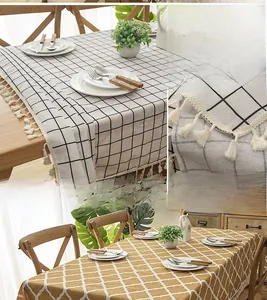 Detail of thick blended tablecloth with black grid, yellow patterns and white tassels