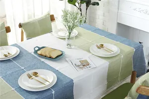 Detail of blue and green jacquard tablecloth with elegant white lace trim and tassels