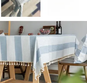 Close-up of blue striped linen tablecloth with white decorative tassels and dot pattern