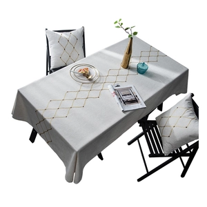 Detailed texture of waterproof tablecloth with golden geometric embroidery on beige linen
