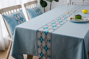 Close-up of waterproof faux linen table runner with light blue and argyle geometric patterns
