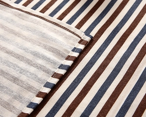Detail of striped cotton linen tablecloth with neat stitching and coarse weave texture