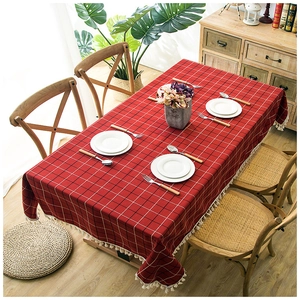 Waterproof red and black checkered tablecloth with white tassels on a wooden dining table