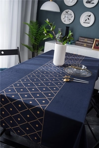 Detail of luxury navy velvet tablecloth with gold geometric diamond patterns and tableware