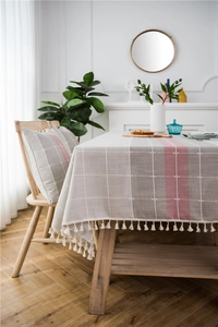 Close-up of gray and pink plaid tablecloth featuring elegant short tassels and matching cushion