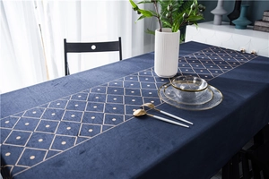 Close-up of luxury velvet tablecloth featuring golden geometric diamond patterns on navy blue