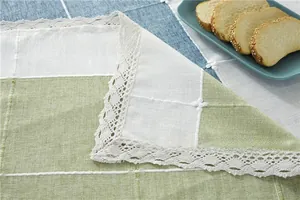Detail of green and white plaid tablecloth featuring elegant lace edges and linen texture