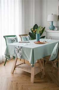 Detail of mint green linen table runner with floral patterns and matching pillows