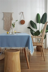 Close-up of light blue linen tablecloth featuring elegant white tassel edges for home decor