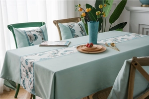 Close-up of mint green linen-like table runner with floral print and matching pillows