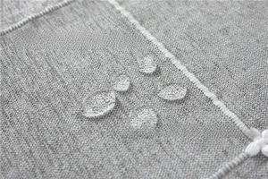 Macro shot of waterproof jacquard fabric with water droplets on grey textured tablecloth