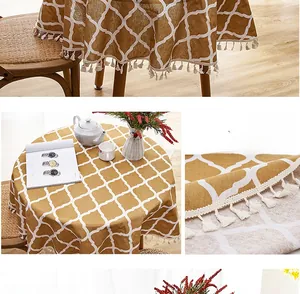 Detail of yellow checkerboard round tablecloth with white fringe trim and linen texture