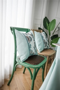 Detailed view of blue vintage floral patchwork cushion on a rustic wooden chair