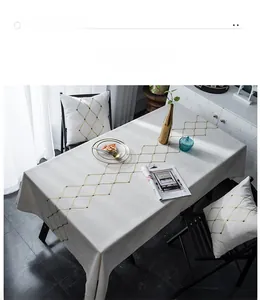 Close-up of geometric diamond embroidery on cream linen tablecloth in a modern home setting