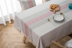 Detail of gray checkered cotton linen table runner with pink stripe and cream tassels