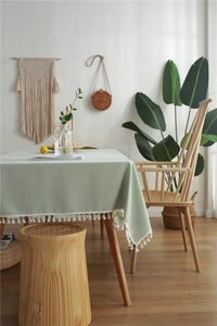 Detail of light green faux linen tablecloth with white tassel edges in Nordic setting