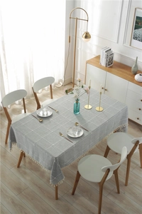 Close-up of grey plaid tablecloth featuring white tassel fringe on a rectangular dining table