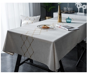 Detail of beige waterproof tablecloth with elegant gold embroidered geometric patterns