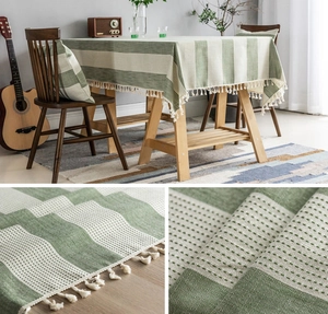 Detail of green and beige striped waffle weave tablecloth with decorative cream tassels