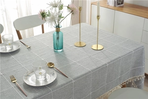 Detailed close-up of grey plaid tablecloth featuring white tassel edges and linen texture