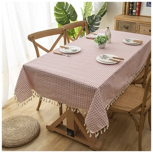 Modern minimalist pink and white plaid tablecloth with tassel edges on a wood table