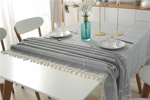 Detail of grey checkered linen-textured tablecloth with elegant white tassels and grid pattern