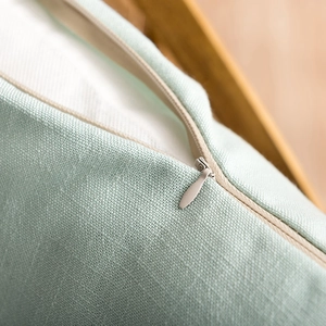 Close-up of invisible zipper detail on mint green faux linen tablecloth fabric