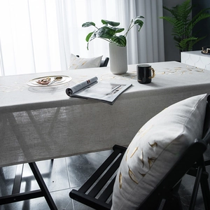 Close-up of golden feather embroidery on cream linen tablecloth with rich fabric texture