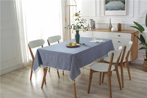 Detail of grey-blue linen tablecloth featuring delicate white fringe tassel edges