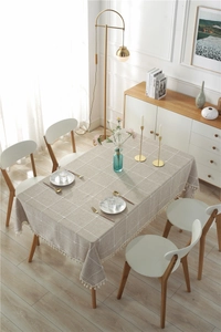 Close-up of beige plaid cotton linen tablecloth with delicate white tassel fringe details
