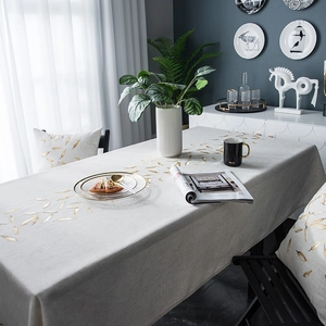 Detail of waterproof linen tablecloth featuring gold leaf patterns and matching cushion cover