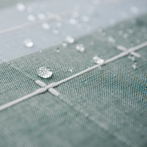 Waterproof Nordic plaid table runner with green checkered fabric showing water beads