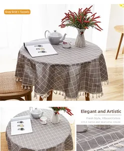 Detail of gray checkered linen-blend round tablecloth with elegant white fringe tassels