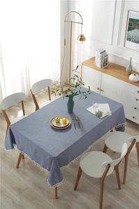 Detail of dark blue rectangular tablecloth featuring white tassels and cotton-linen texture