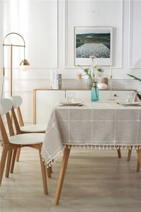 Detail of oatmeal linen tablecloth with white grid patterns and fringe edge