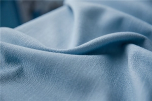 Detailed macro view of light blue linen-textured fabric with natural weave and soft draping
