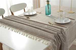 Close-up of light brown plaid cotton linen tablecloth with delicate white tassel fringe detail