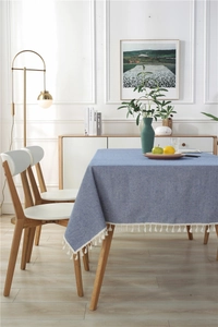Close-up of blue textured linen tablecloth featuring decorative white tassel fringe details