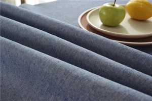 Detail of blue textured cotton-linen tablecloth with tassel edge and natural weave texture