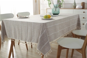 Close-up of beige jacquard tablecloth with white geometric weave and fringe tassels