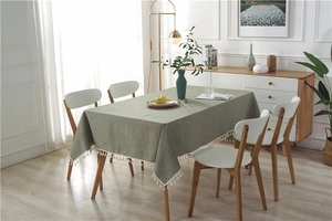 Detail of olive green cotton tablecloth with fringe tassels in a Nordic dining room