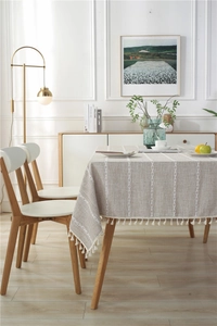 Detail of beige table cloth with vertical white embroidery and elegant fringe edges