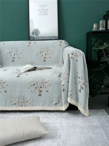 Detail of light blue chenille sofa cover with tree pattern and white lace edging