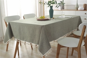Detail of dark green rectangle tablecloth with white tassel trim and fabric texture